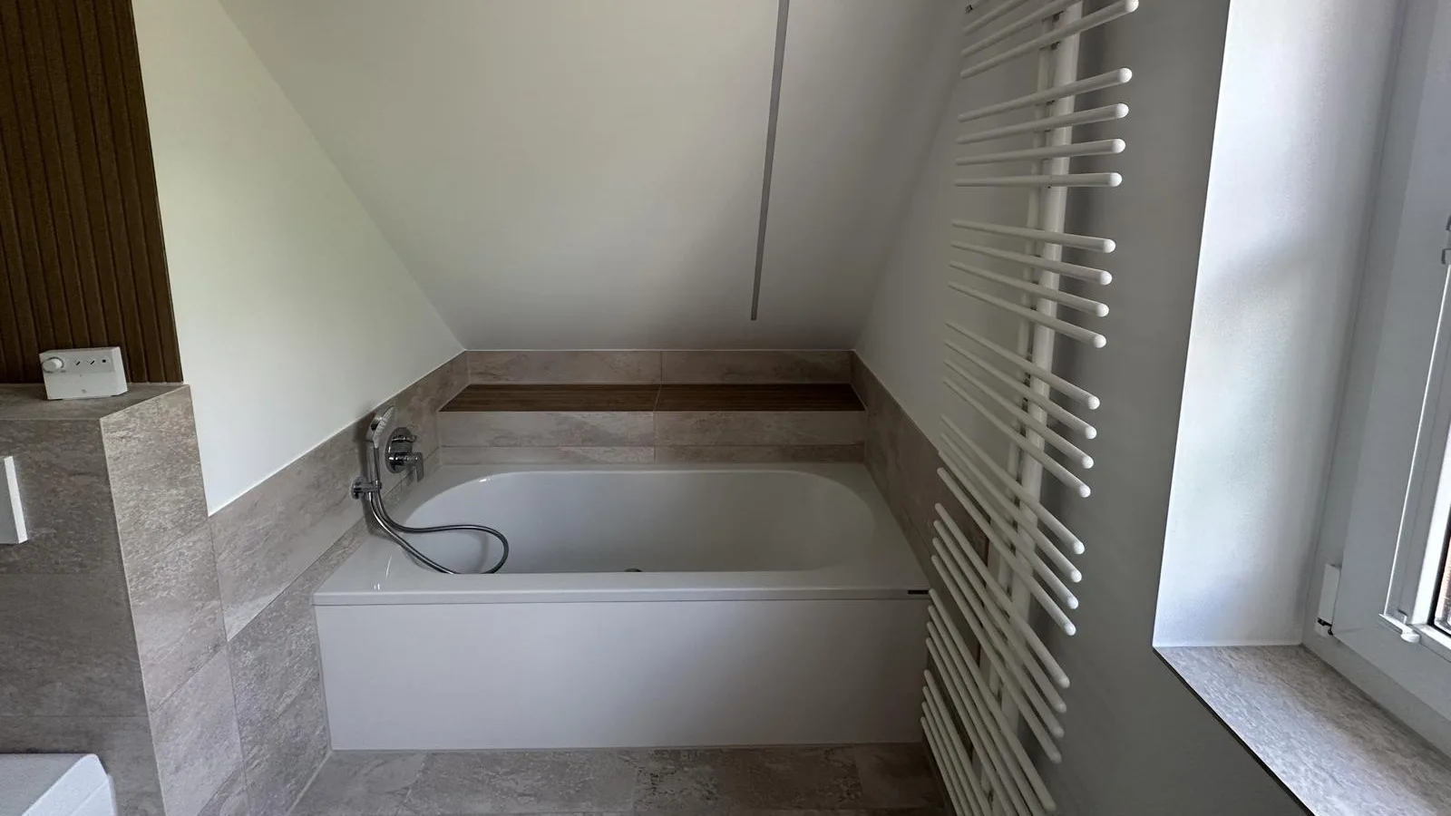Badewanne unter der Dachschräge mit Ablage hinter der Wanne